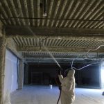 Worker removing Fireproofing material from ceiling